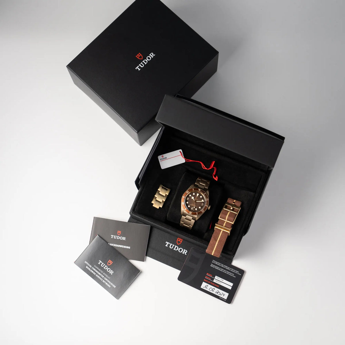 Lieferumfang zu der Tudor Black Bay 58 M79012M in Bronze, deren Oberfläche bereits mit einer gleichmäßigen Patina überzogen ist, mit einem braunem Zifferblatt, betsehend aus Box mit Umkarton, Garantiekarte, Hangtag, Booklets und zusätzlichem Nato-Armband