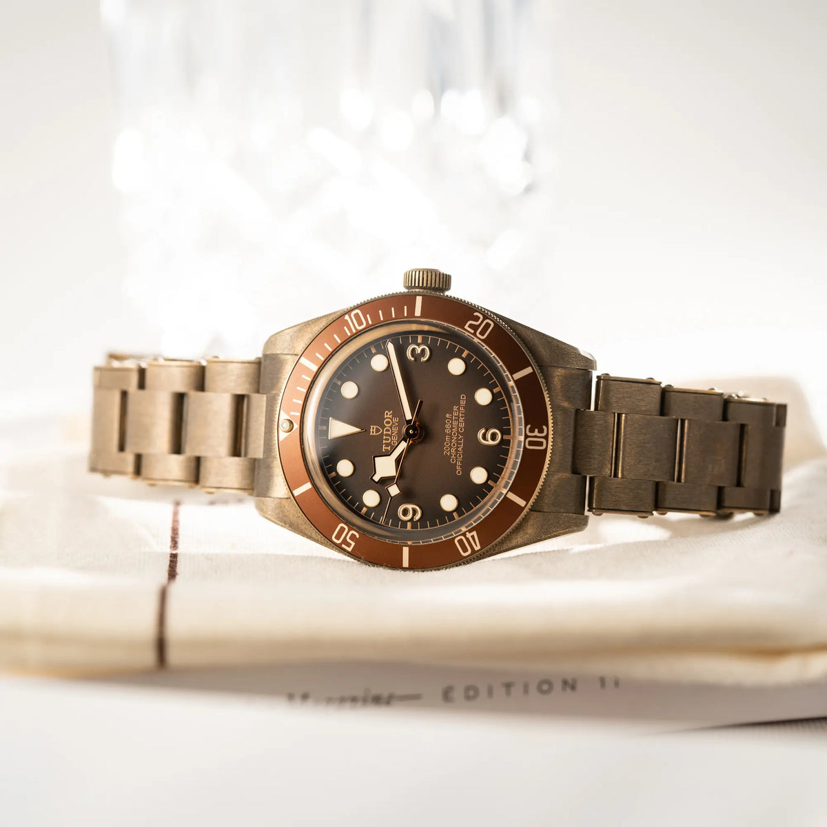Produktfotografie der seitlich auf dem Gehäuse liegenden Tudor Black Bay 58 M79012M in Bronze, deren Oberfläche bereits mit einer gleichmäßigen Patina überzogen ist, mit einem braunem Zifferblatt