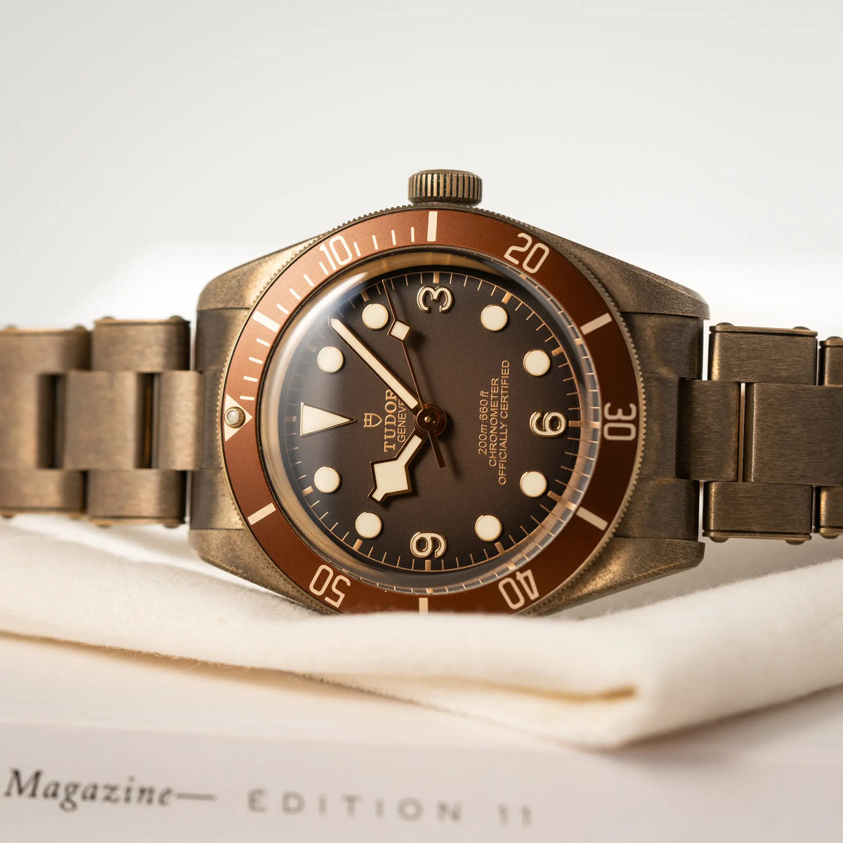NaProduktfotografie der Tudor Black Bay 58 M79012M in Bronze, deren Oberfläche bereits mit einer gleichmäßigen Patina überzogen ist, mit einem braunem Zifferblatt mit Fokus auf dem Uhrenkopf