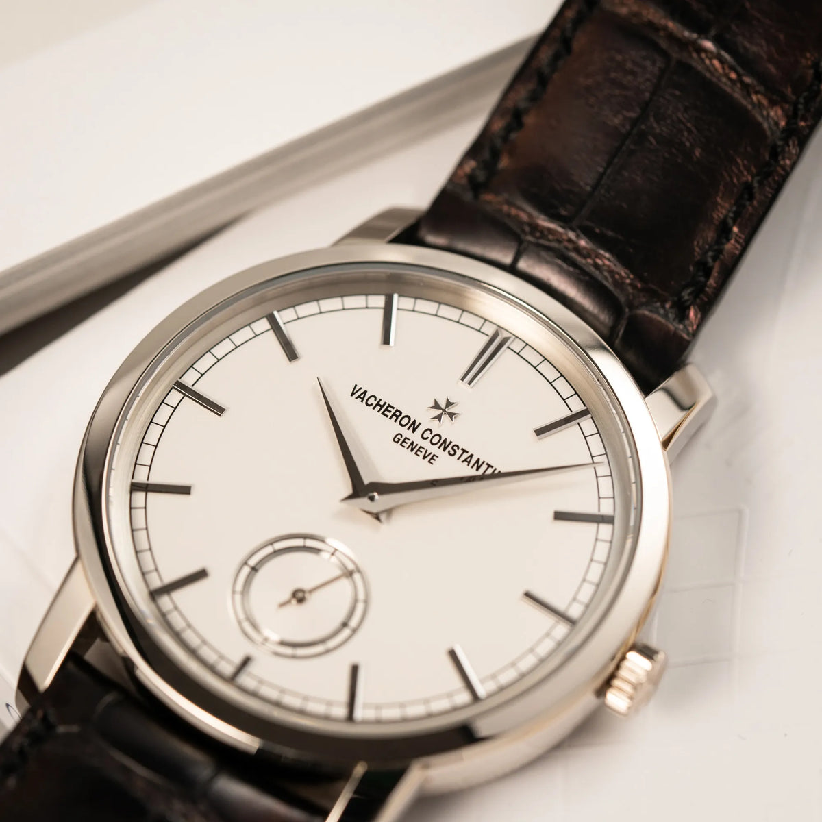 Detailaufnahme der Vacheron Constantin Traditionelle 82172 mit weißem Zifferblatt und einem Weißgold-Gehäuse am braunem Lederband mit Fokus auf dem "Vacheron Constantin Geneve" Schriftzug