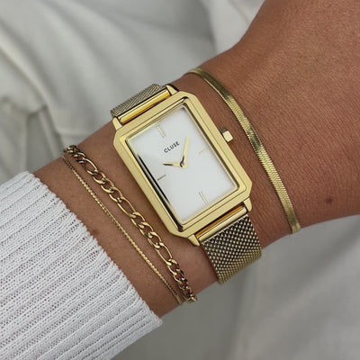 Frau trägt die Cluse Stahl-Uhr "Fluette" mit gelbgoden-farbigem Gehäuse und weißem Zifferblatt an Ihrem handgelenk und präsentiert diese mit einem Wrist-Roll